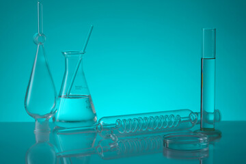 Over a blue background, erlenmeyer flask, a tube with spiral pipe inside, test tube and a petri...