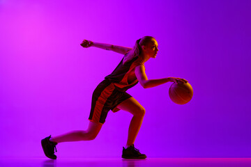 Young girl, concentrated female basketball player in motion, dribbling ball, training against white...