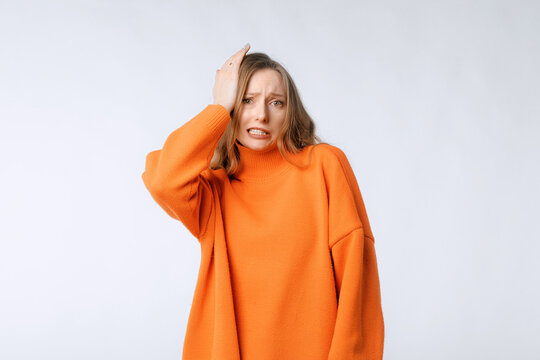 Portrait Of Confused Attractive Female Feeling Awkward, Lifting Eyebrows And Looking At Camera With Weird Smile After Making Mistake And Being Guilty, Saying Oops, Standing Over Neutral Background