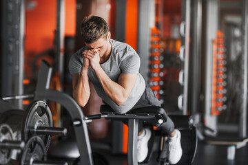 Young handsome fit man performing hyperextension exercise on roman chair at gym.