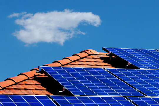 roof installed photovoltaic PV sun collector solar panels. clear blue sky red clay sloped residential roof in daylight. alternative and clean energy generation. self sufficiency and off grid concept.