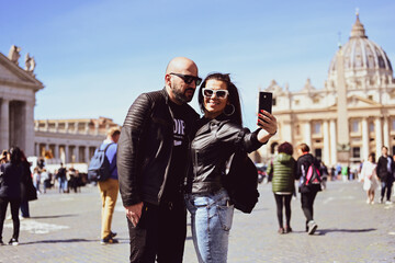 Obraz premium Happy smiling beautiful Tourists couple traveling at Rome, Italy, poses and making photos in front of Vatican City at, Rome, Italy.Concept of Italian gastronomy and travel. Italian couple having