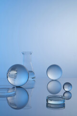 Petri dishes and erlenmeyer flask filled transparent liquid, transparent balls and reflection on...