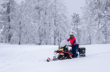 Fototapeta na wymiar An athlete on a snowmobile moves through the winter forest in the mountains of the Southern Urals