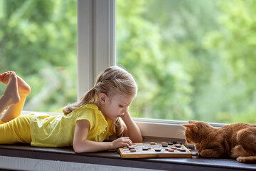Girl plays checkers with a cat. Board intellectual games.
