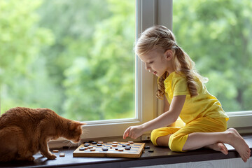 Girl plays checkers with a cat. Board intellectual games.