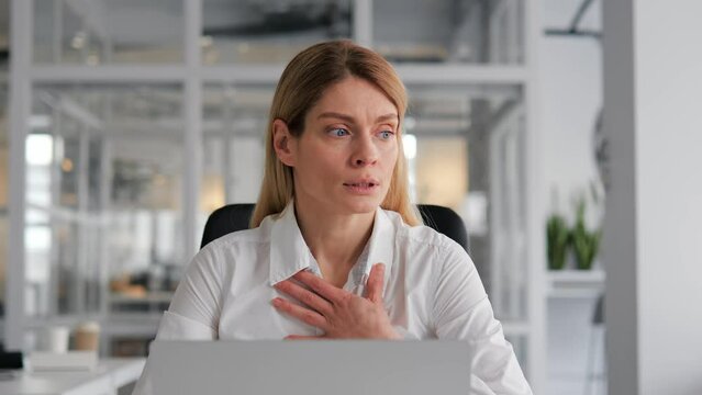 American freelance businesswoman feeling unwell experiencing panic attack having difficulty breathing. Woman touches chest in office, virus, pandemic, disease, epidemic, infection, arrhythmia.