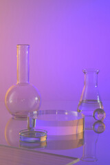 Equipment of the chemical laboratory - glass flask and petri dish containing transparent decorated on gradient background. Empty podium for cosmetic product presentation.