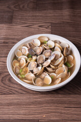 braised fresh White Sea clam shell in Chinese wine ginger onion and scallion soup in white bowl on wood table luxury halal food fine dining restaurant seafood menu