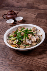 braised fresh White Sea clam shell in Chinese wine ginger onion and scallion soup in white bowl on wood table luxury halal food fine dining restaurant seafood menu