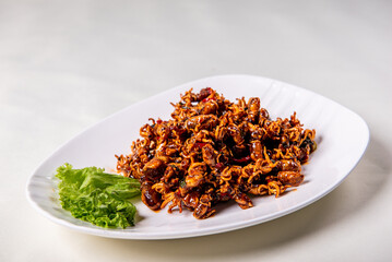 grilled golden deep fried baby squid cuttle fish octopus and cucumber in fresh honey spicy fish gravy sauce in white plate on wood table luxury halal food fine dining seafood restaurant appetiser menu
