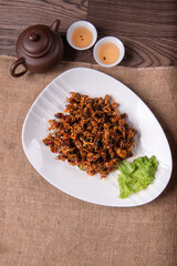 grilled golden deep fried baby squid cuttle fish octopus and cucumber in fresh honey spicy fish gravy sauce in white plate on wood table luxury halal food fine dining seafood restaurant appetiser menu