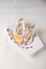 fresh western seafood raw big oyster shell with lemon in white cold plate on wood table luxury halal food fine dining restaurant menu