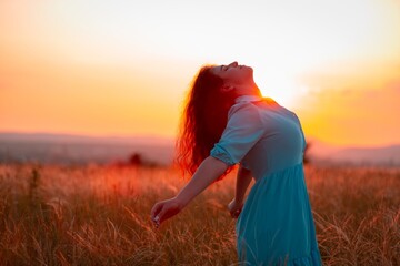 Woman on field wheat with sunset background