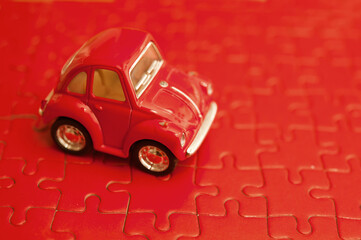 red toy car on red jigsaw puzzle 