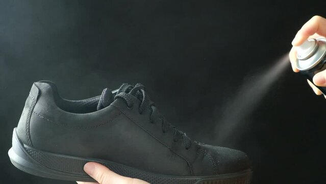 The process of applying a water-repellent spray to black men's nubuck demi-season shoes
