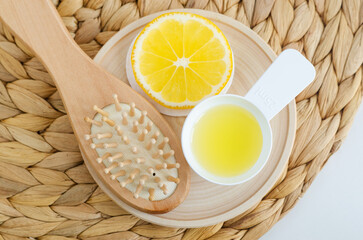 Lemon juice, lemon slice and wooden hairbrush. Ingredients for preparing homemade hair toner or beauty mask. Natural hair care, homemade spa and beauty treatment recipe. Top view