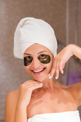 woman in bathroom applying black eye patches. Skin care and spa morning concept