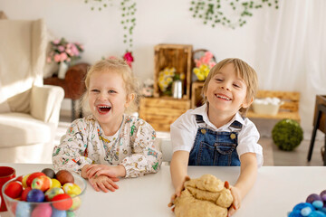 Little blond toddler boy child with sister, preparing dough for easter brioche buns, sweet easter bread with nuts and dry fruits