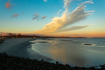 Obraz premium Beautiful sea with a view of the city during orange sunset