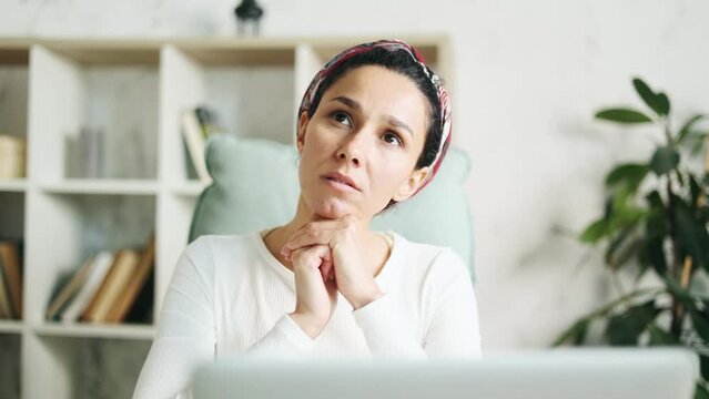 Portrait of pretty creative hispanic woman designer thinks questioningly about difficult choice choose something imagine plan in mind has doubts create idea at desk next to laptop at home workplace