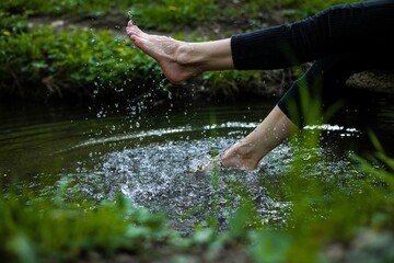 Girl tapping water with legs in a forest during the day