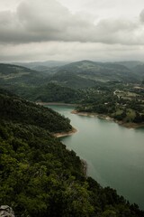 Aerial view of Rovni Lake surrounded by green vegetation under gray cloudy sky in western Serbia