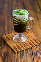 ice cendol in glass on wooden table
