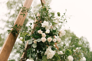 Details of the wedding decor, the arch for the newlyweds made of wood decorated with fresh flowers...