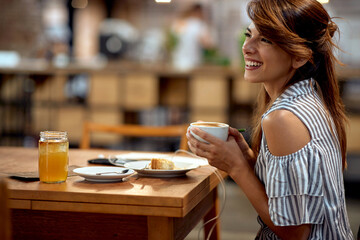 Beautiful young girl enjoying cup of coffee alone. Cheerful young woman in cafe.