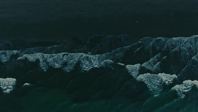Aerial of calm sea waves rolling on an empty sandy beach at sunset in Ecuador.