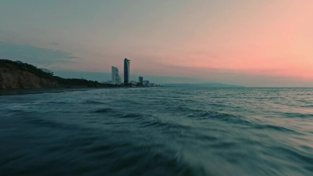 Aerial of calm sea waves rolling on Tonsupa beach at sunset in Ecuador.
