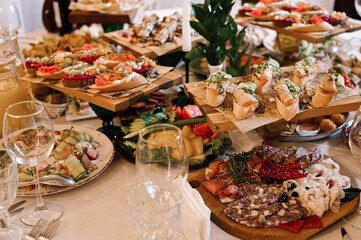 A set of Italian snacks for a buffet. A variety of cheeses, cold cuts bruschetta, pickled cucumbers, tomatoes on a wooden background