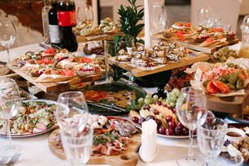 A set of Italian snacks for a buffet. A variety of cheeses, cold cuts bruschetta, pickled cucumbers, tomatoes on a wooden background
