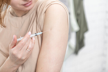 Young woman doing injection in her arm herself at home