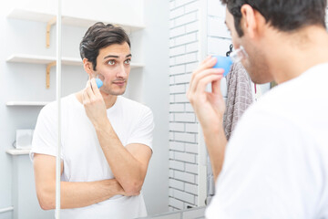 Handsome man standing in front of the mirror and doing facial massage with vacuum cups. Skin care and healthy lifestyle concept