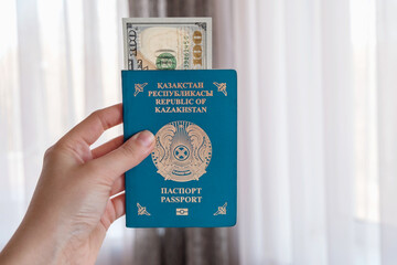 National passport Republic of Kazakhstan in the hand. Travel, citizenship, relocation, immigration or bribe concept. Dollars in the passport