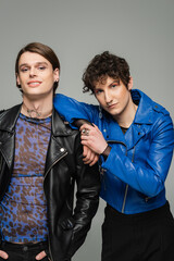 fashionable pansexual partners with makeup looking at camera isolated on grey.