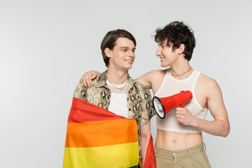 happy bigender partners with loudspeaker and lgbt flag looking at each other isolated on grey.