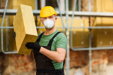 Builder holds mat of mineral wool for insulating buildings. Space for text.