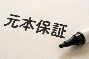 元本保証と書かれたノートとマーカー
