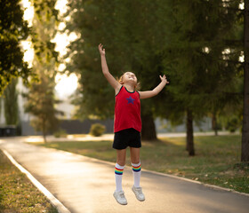 Happy cute kid girl child in sport wear jumping in a park and smiling. Summer sport activity concept. Happy childhood.