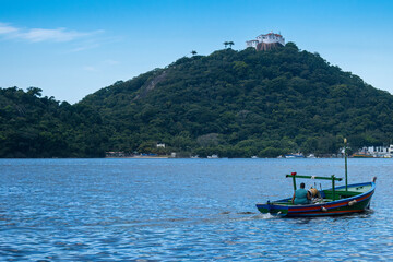 Fototapeta na wymiar Penha Convent in the background and a fisherman driving a boat in the foreground.