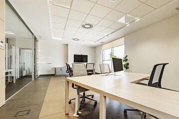 An office with a meeting area, desks, TV screens and computers on the tables