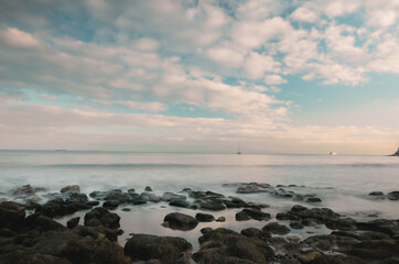 Obraz premium Long exposure of a sunset by the sea and a rocky coast