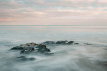 Long exposure of a sunset by the sea and a rocky coast