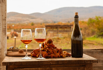 on the old table there is a bottle of wine, two glasses and dried fruit