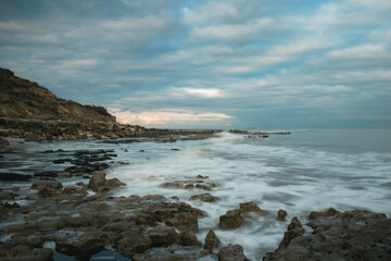 Fototapeta na wymiar Long exposure shot of waves washing onto a rocky shore