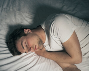 A man sleeping on a white bed