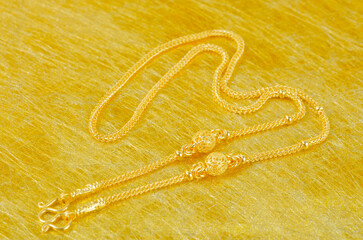 A Gold necklace on gold color background.
